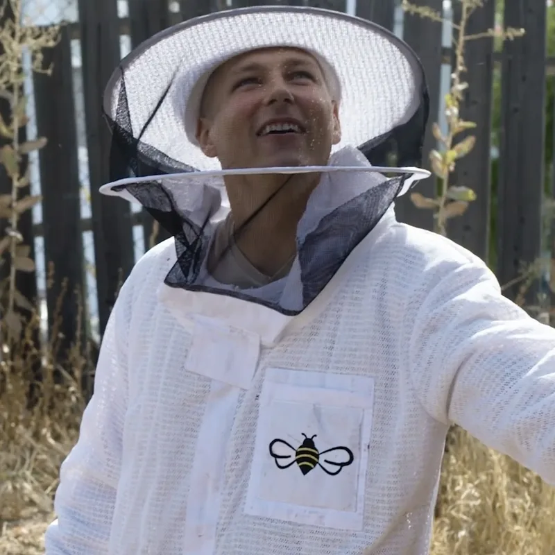 Eli the Bee Guy in his beekeeper suit and veil at a live bee removal in Southern California